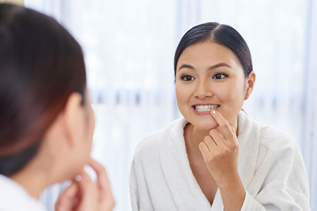 young-Asian-woman-looking-at-her-teeth-in-the-mirror