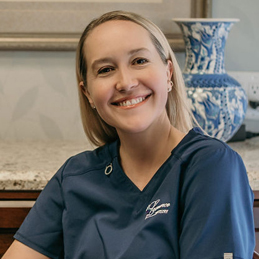 a blonde girl with a big smile wearing a blue shirt