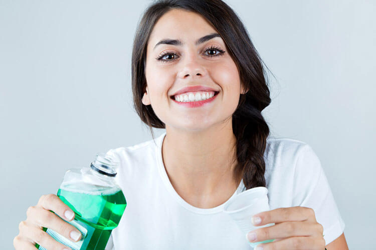 lady holding a bottle of mouthwash and a cup