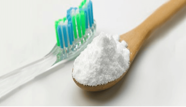 a toothbrush and a spoon of baking soda