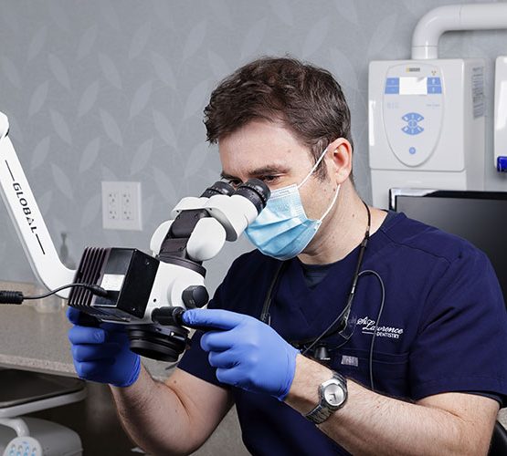 doctor wearing a facemask looking through a microscope