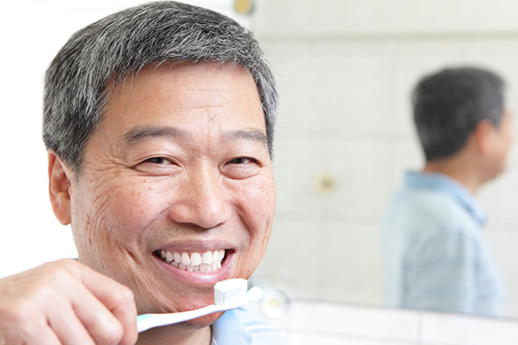 old man holding toothbrush while smiling