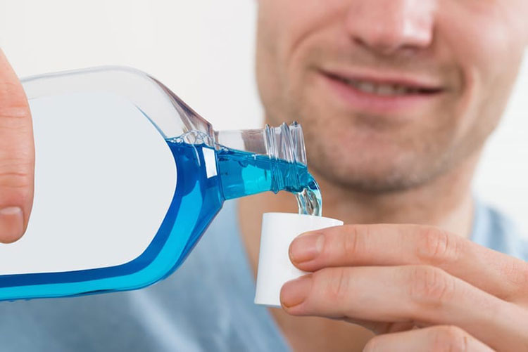 man pouring blue liquid in a small cup