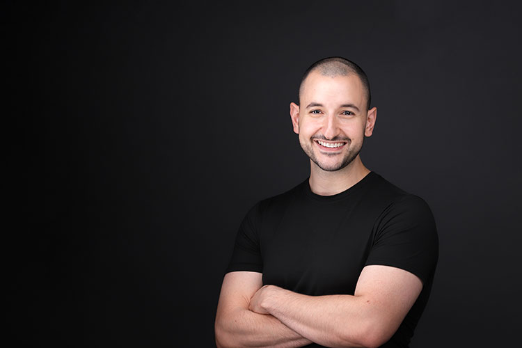 smiling man wearing a black t-shirt with a black background