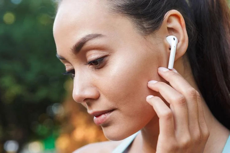 a woman wearing earpods holding her jaw